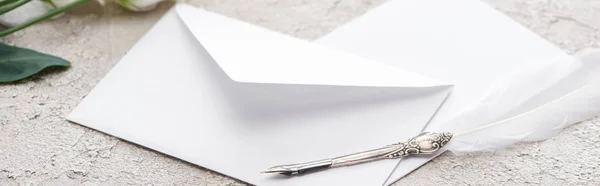 Panoramic shot of envelopes and quill pen on grey textured surface — Stock Photo