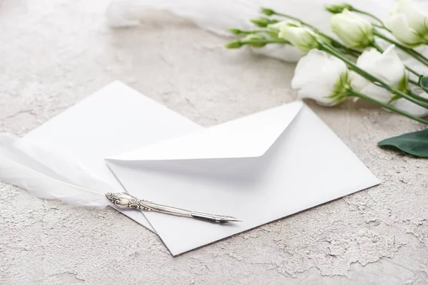 White envelope near eustoma flowers and quill pen on grey textured surface — Stock Photo