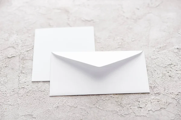 White paper envelope and card on grey textured surface — Stock Photo