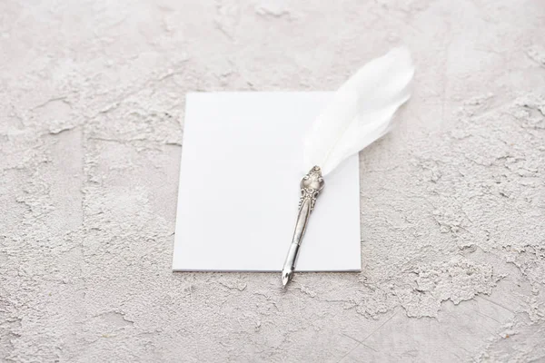 Stylo plume sur carte blanche vide sur surface grise texturée — Photo de stock