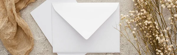 Plan panoramique de l'enveloppe blanche près des fleurs et sac beige sur surface texturée — Photo de stock