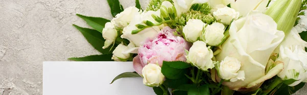 Tiro panorâmico de cartão branco perto de buquê de flores na superfície texturizada — Fotografia de Stock