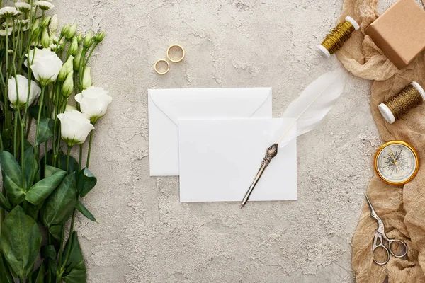 Вид зверху на порожню картку, квіти еустоми, обручки, подарункова коробка, компас, ножиці та бульбашки на бежевому весіллі на текстурованій поверхні — стокове фото