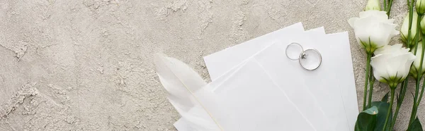 Tiro panorâmico de anéis de prata em cartões de convite perto de flores eustoma branco na superfície texturizada — Fotografia de Stock