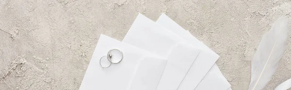 Panoramic shot of silver rings on white envelopes on textured surface — Stock Photo