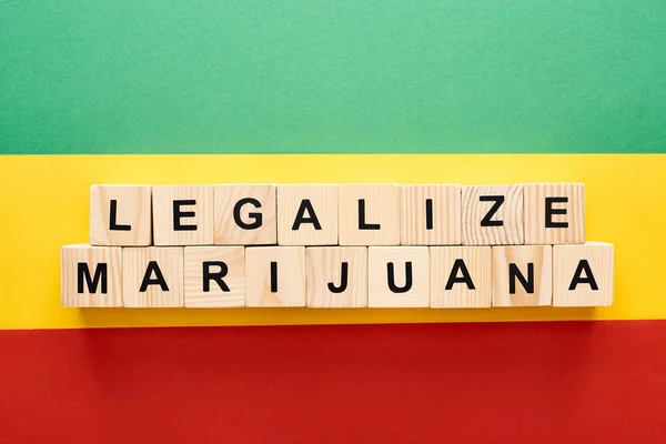 Top view of wooden blocks with legalize marijuana lettering on Rastafarian flag background — Stock Photo