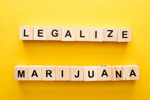 Vue du dessus des blocs de bois avec légaliser le lettrage de marijuana sur fond jaune — Photo de stock