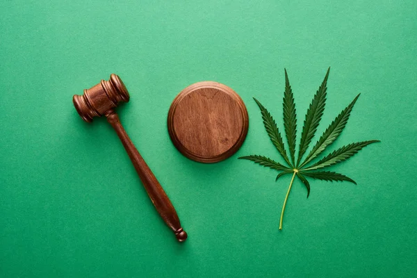 Top view of green marijuana leaf with wooden gavel on green background — Stock Photo