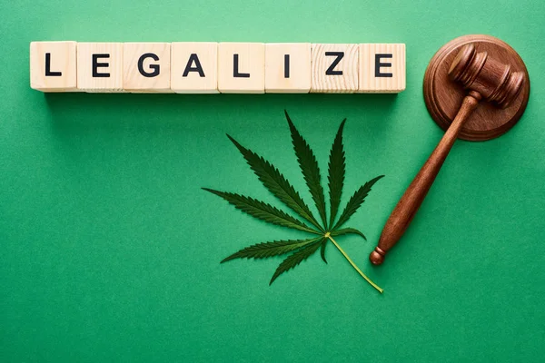 Ansicht des grünen Cannabisblattes, legalisierter Schriftzug auf Holzklötzen und Hammer auf grünem Hintergrund — Stockfoto