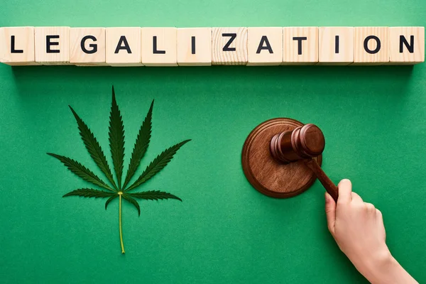 Cropped view of woman holding wooden gavel near cannabis leaf and legalization lettering on wooden blocks — Stock Photo