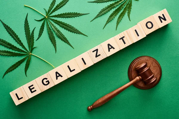 Vue du haut des feuilles de cannabis vert et mot de légalisation sur les blocs de bois près du marteau sur fond vert — Photo de stock