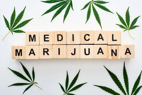 Top view of cannabis leaves and wooden blocks with medical marijuana words on white background — Stock Photo