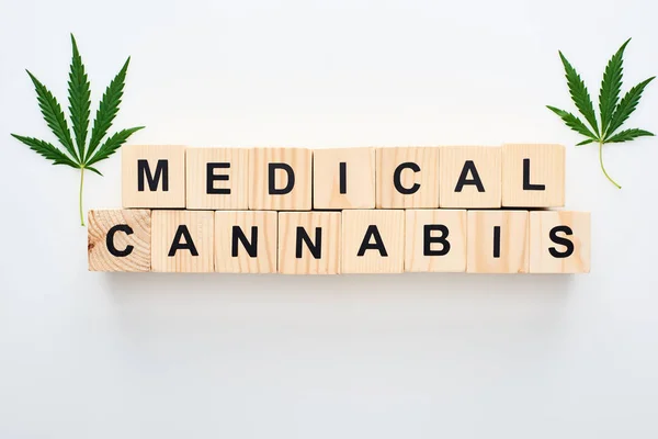 Top view of cannabis leaves and wooden blocks with medical cannabis words on white background — Stock Photo