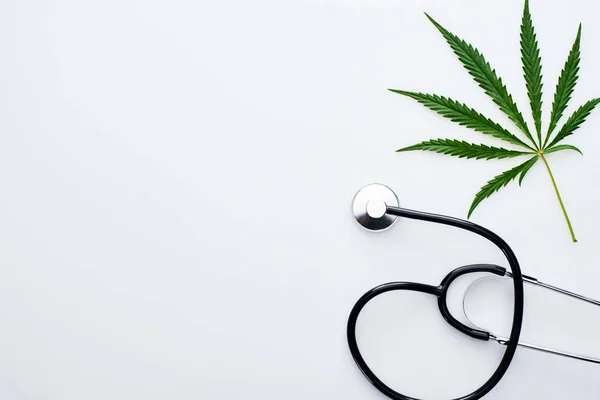 Top view of medical cannabis leaf near stethoscope on white background — Stock Photo