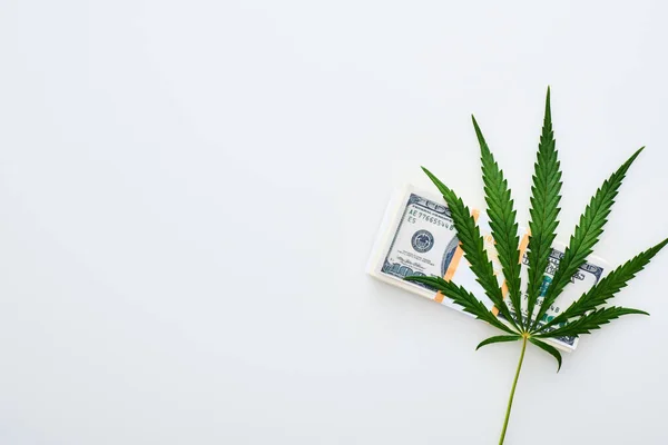Vista superior de la hoja de cannabis medicinal cerca de billetes de dólar sobre fondo blanco con espacio para copiar - foto de stock