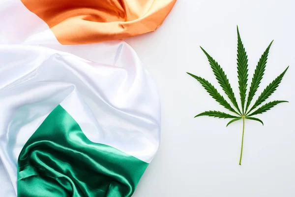 Vista superior da folha de cannabis verde perto da bandeira da Irlanda no fundo branco — Fotografia de Stock