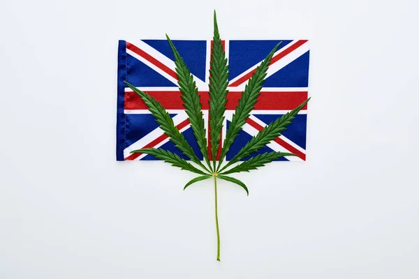 Draufsicht auf grünes Cannabisblatt auf britischer Flagge auf weißem Hintergrund — Stockfoto