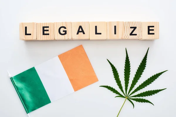 Vue du dessus de la feuille de cannabis verte et légaliser le lettrage sur des cubes en bois près du drapeau de l'Irlande sur fond blanc — Photo de stock