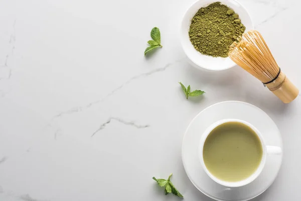 Blick von oben auf grünen Matcha-Tee mit Minze auf weißem Tisch — Stockfoto