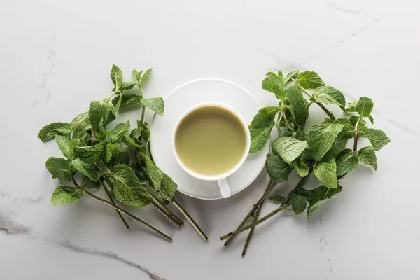 Vista superior de té matcha verde y menta sobre mesa blanca - foto de stock