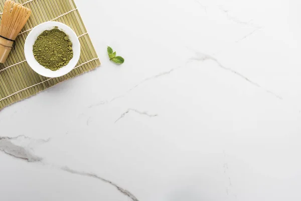 Top view of green matcha tea powder and whisk on white table — Stock Photo