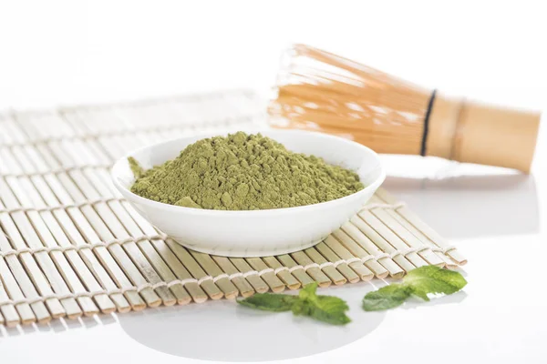 Matcha green tea powder with whisk on bamboo mat — Stock Photo
