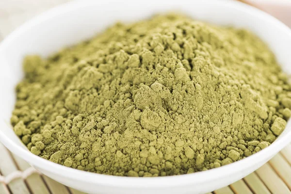 Close up of matcha green tea powder in bowl on bamboo mat — Stock Photo