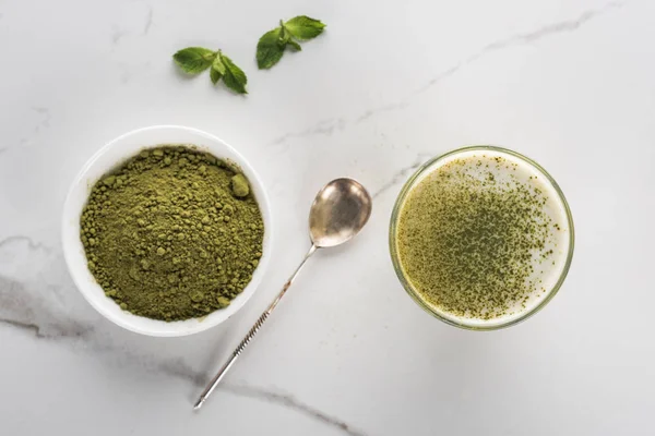 Top view of matcha tea powder and drink in glass on white table — Stock Photo