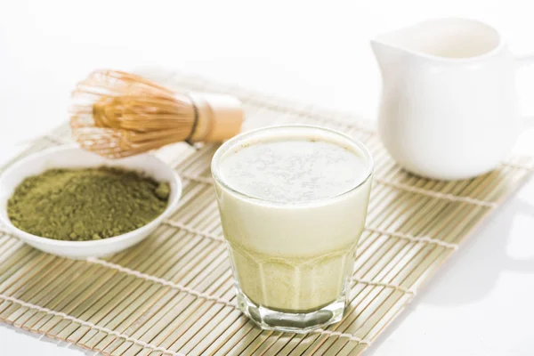 Té matcha verde con leche en estera de bambú - foto de stock