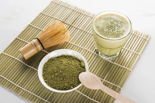 Green matcha tea, whisk and spoon on bamboo mat — Stock Photo