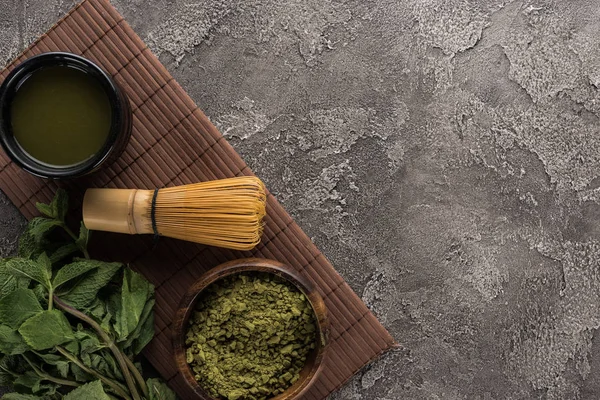 Vista superior do chá tradicional matcha com batedor no tapete de bambu na mesa de pedra escura — Fotografia de Stock