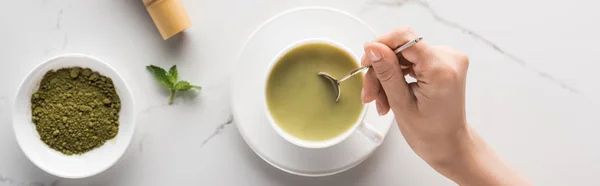 Cropped view of woman holding matcha matcha tea on table — Stock Photo