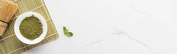 Vista dall'alto del tè verde matcha in polvere sul tappetino di bambù sul tavolo bianco — Foto stock