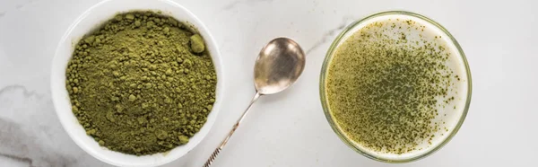 Vista superior de polvo de té matcha verde y beber en vidrio sobre mesa blanca - foto de stock