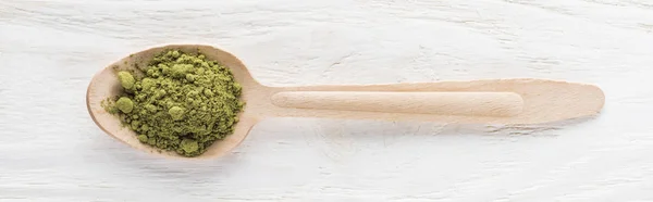 Top view of wooden spoon with powder of green matcha tea on white table — Stock Photo