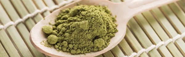 Closeup of wooden spoon with powder of green matcha tea on bamboo mat — Stock Photo