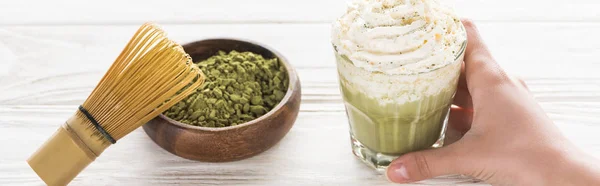 Vista cortada da mulher segurando o chá matcha matcha com chantilly na mesa com uísque e pó — Fotografia de Stock