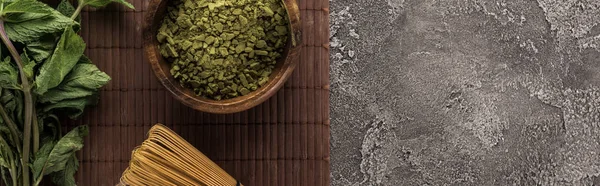 Vista superior de té matcha verde y menta en estera de bambú en mesa de piedra oscura - foto de stock