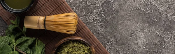 Vue du dessus du thé vert matcha traditionnel sur un tapis de bambou sur une table en pierre sombre — Photo de stock