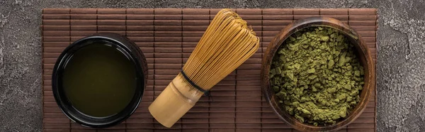 Vue du dessus de la poudre de thé matcha vert sur tapis de bambou sur table en pierre sombre — Photo de stock