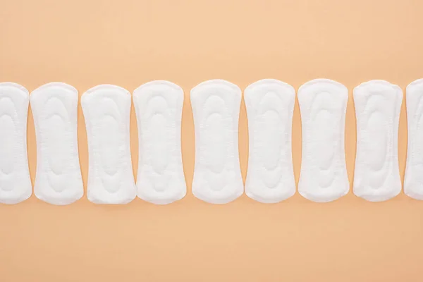 Flat lay with white cotton sanitary towels isolated on beige — Stock Photo