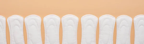 Row of white cotton sanitary towels isolated on beige, panoramic shot — Stock Photo