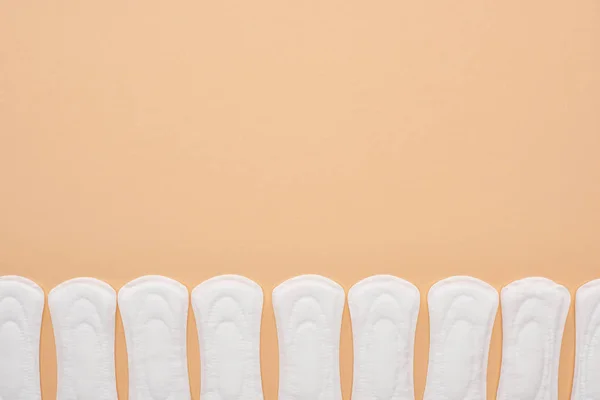 Row of white cotton sanitary towels isolated on beige — Stock Photo