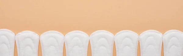 Flat lay with white cotton sanitary towels in row isolated on beige, panoramic shot — Stock Photo