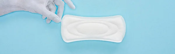 Top view of white paper hand holding cotton sanitary towel on blue background, panoramic shot — Stock Photo