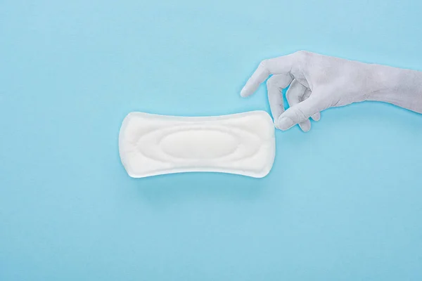 Vue du dessus de la main en papier blanc et serviette hygiénique en coton sur fond bleu — Photo de stock