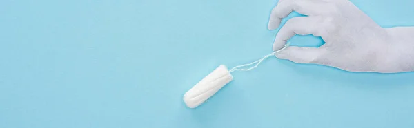 Top view of white paper hand holding cotton tampon on blue background, panoramic shot — Stock Photo