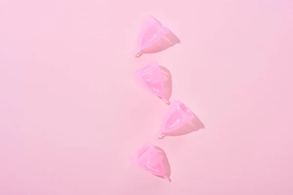 Vista superior de copos menstruais de plástico rosa no fundo rosa — Fotografia de Stock