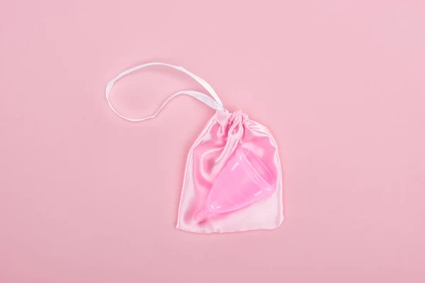 Top view of pink plastic menstrual cup in bag on pink background — Stock Photo