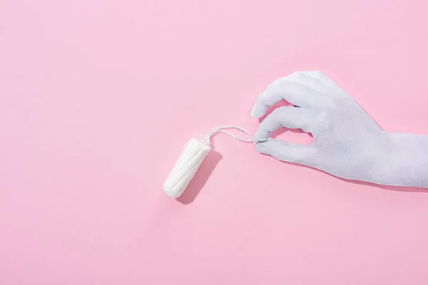 Top view of white paper cut hand holding cotton tampon on pink background — Stock Photo